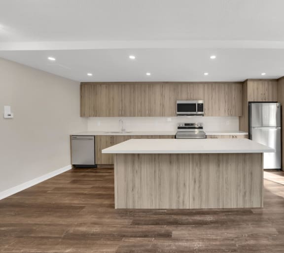 a kitchen with a large center island with a stove top oven and a refrigerator