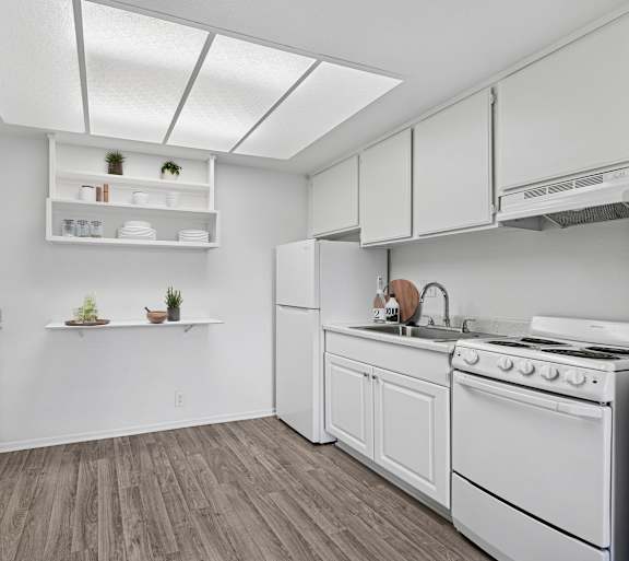 A kitchen with white appliances and wooden floors.