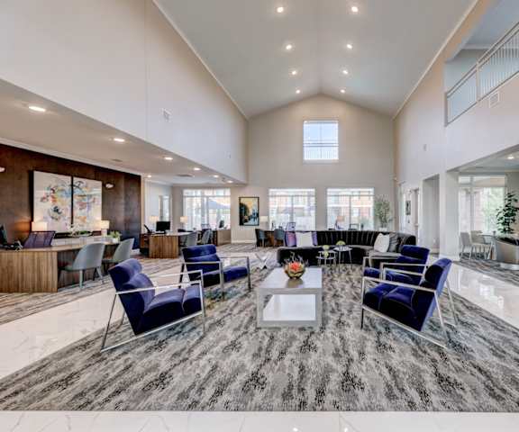 The resident lounge with a fireplace, couches, desks, decorations, plush chairs, and coffee tables at Indigo Apartments. 
