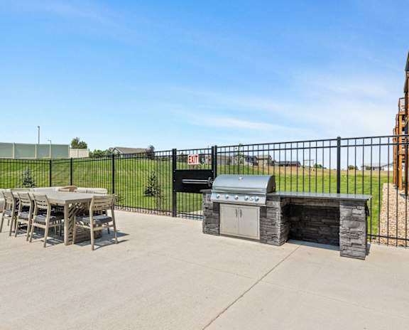 a patio with a grill and a table and chairs