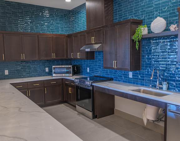 A kitchen with brown cabinets and a blue tile backsplash.