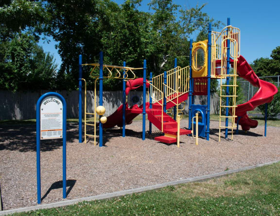 a playground with a red slide and yellow monkey bars