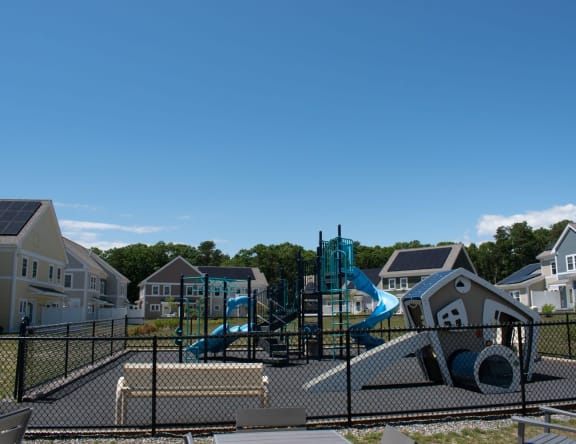 a playground with slides and other equipment in front of a row of houses