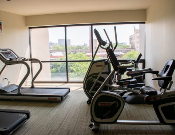a gym with cardio equipment and a large window