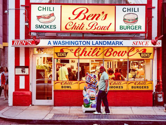 a man standing outside of a chili bowl restaurant on a city street