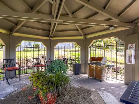A covered patio with a table and chairs.