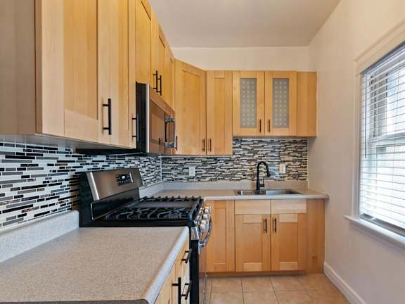 A kitchen with wooden cabinets and a black stove top oven.
