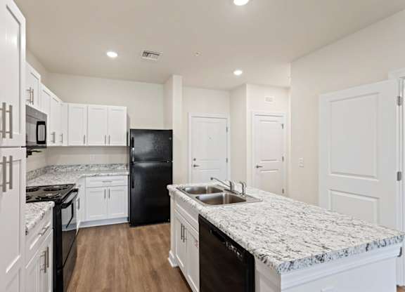 Peaks of Lexington Apartments Kitchen with Black Appliances, Granite Countertops and White Cabinetry and connected living room