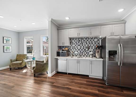A kitchen with a refrigerator, cabinets, and a dining table.