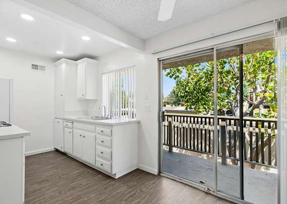 A white kitchen with a sliding glass door leading to a deck.