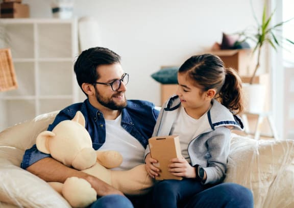 a man and a girl sitting on a couch looking at a tablet computer