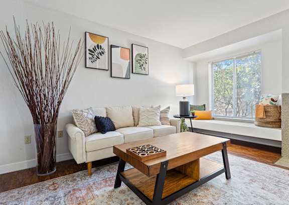 A living room with a white couch, a wooden coffee table, and a vase with brown branches at MonteVista Apartments, Beaverton, Oregon