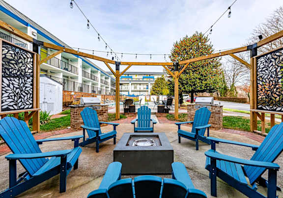 A patio with blue chairs and a fire pit.