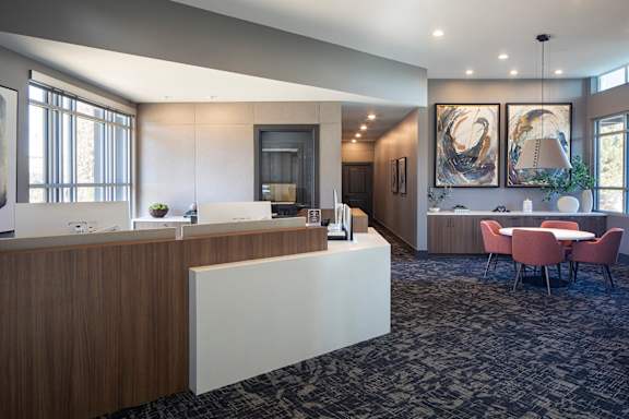 A reception area with a white reception desk and a grey carpet.