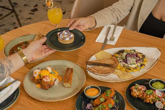 A person is having a meal at a restaurant with a variety of dishes in front of them.