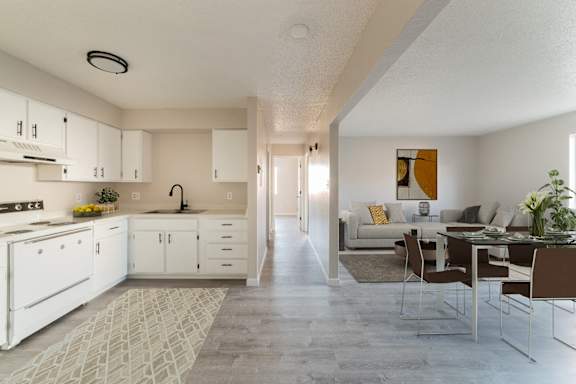 A kitchen with white cabinets and a dining table with chairs.