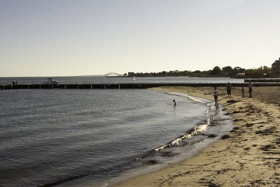 People walking on the beach near the water at Brookwood at Bay Shore in Bay Shore, NY 11706