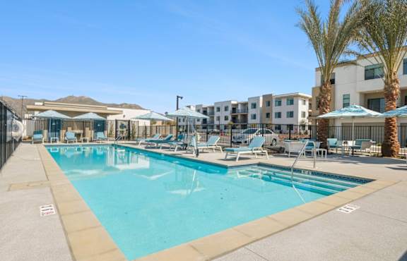 A large swimming pool with lounge chairs and umbrellas.