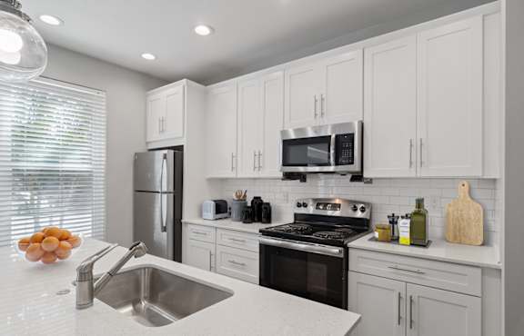A modern kitchen with white cabinets and stainless steel appliances.