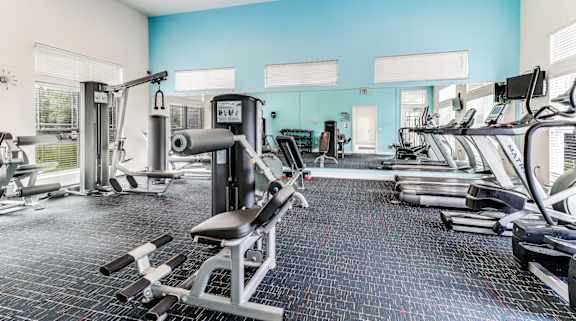 A spacious gym with a variety of equipment including treadmills, weight machines, and free weights.
