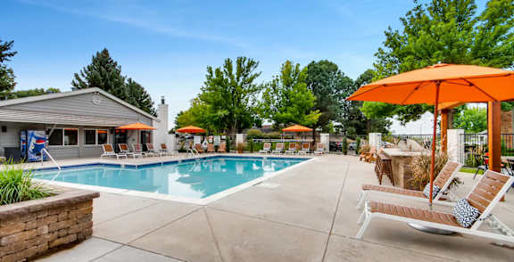 A pool area with a clear blue sky and a white building in the background.