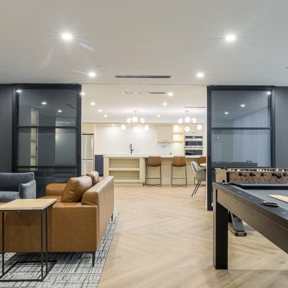 a living room with a pool table and a kitchen