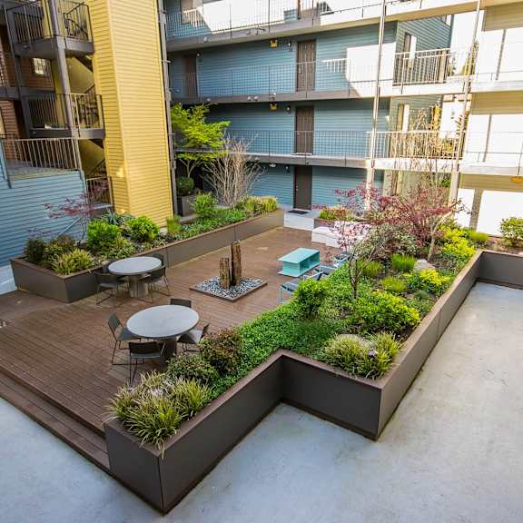 a courtyard with a table and chairs on a wooden deck