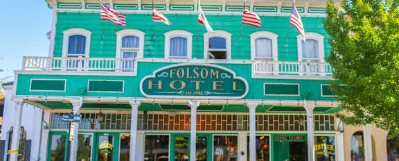 A green building with the name Folsom Hotel on it.