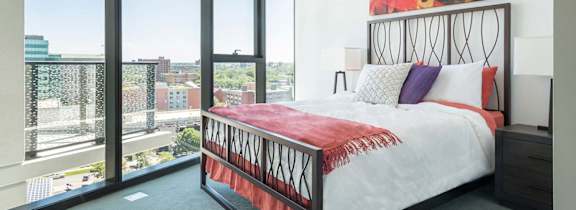 A bedroom with a large bed and a view of the city.