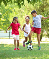 Kids playing with soccer ball in grass