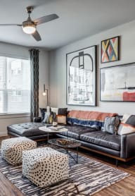 a living room with a leather couch and three windows