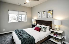 A bedroom with a bed, nightstand, and a window.