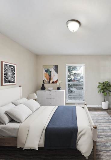 A bedroom with a bed, nightstand, and two framed pictures on the wall.