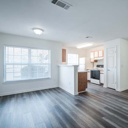 A spacious living room with a kitchenette in the background.at The Regency Apartment Homes, Manassas, 20109