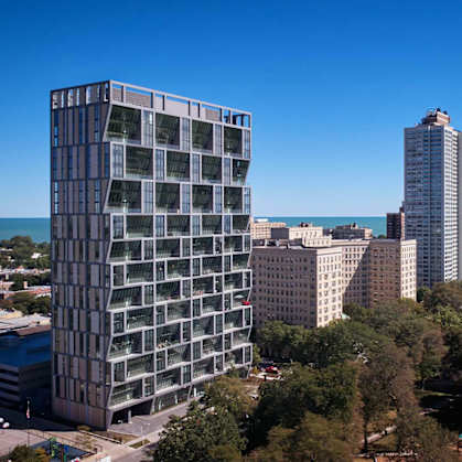 A modern glass building stands out among the other buildings in the city.