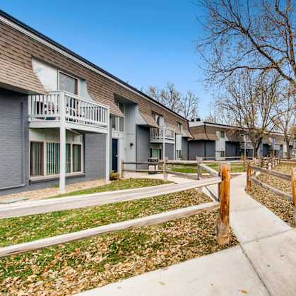 A row of houses with a sidewalk and a tree in front.