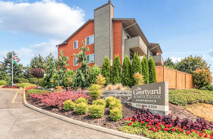 The image shows a building with a sign that reads "The Courtyard Apartments" in front of it.