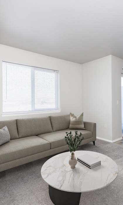 A living room with a grey couch, a white coffee table, and a grey chair.