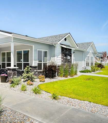 A white house with a grey roof and a small garden in front.