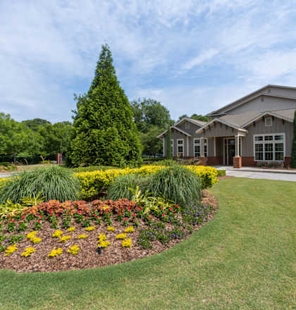 a large lawn with a flower garden in front of a building