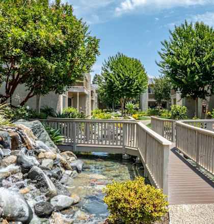 A bridge over a stream in a landscaped courtyard.