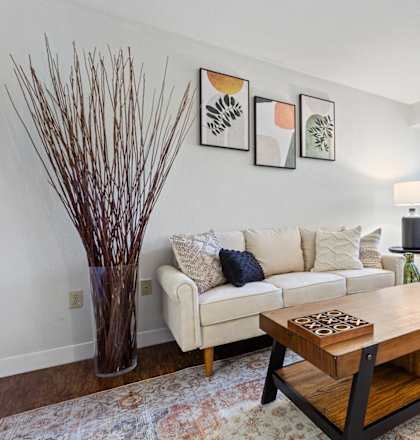 A living room with a white couch, a wooden coffee table, and a vase at MonteVista Apartments, Oregon 97007