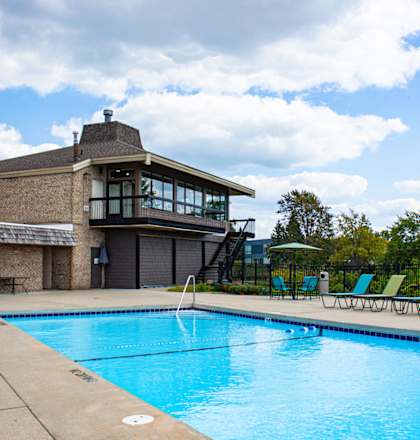 a swimming pool in front of a building with green chairs