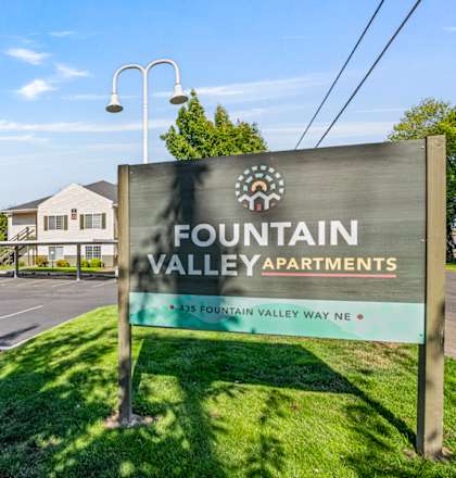 A sign for Fountain Valley Apartments stands in front of a row of houses.