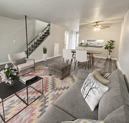 Large living room with carpeted stairs to the left and dining area on the right. Wood-style floors and ceiling fan.at Quilceda Gardens, Marysville, WA