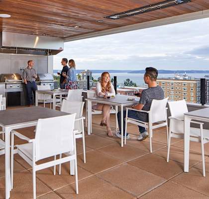 A group of people are gathered around a table in a modern outdoor kitchen.