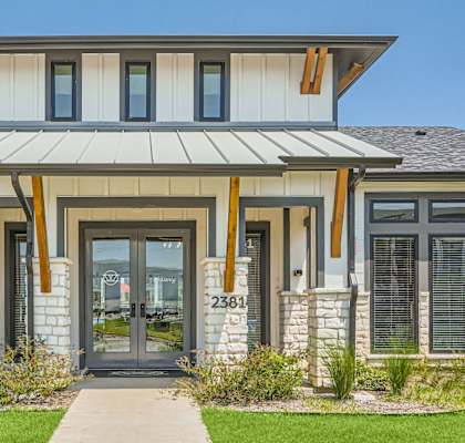 A modern house with a stone pillar and a glass door.