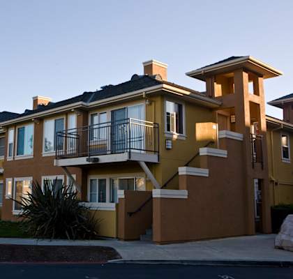 A yellow and brown apartment building with a balcony on the second floor.