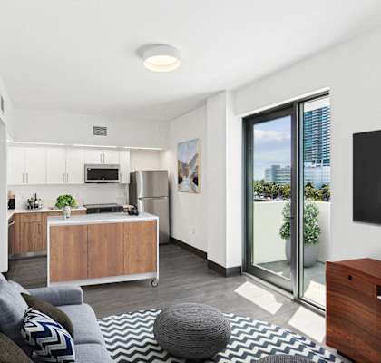 A modern living room with a grey sofa and a grey pouf.