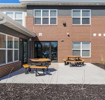 a patio with two picnic tables in front of a brick building